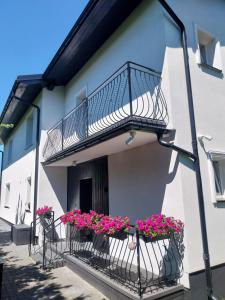 a balcony with pink flowers on a white building at WillaSimi in Władysławowo
