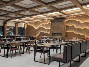 a restaurant with tables and chairs in front of a stone wall at AMZA Valbona Mountain Retreat in Valbonë