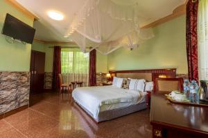 a bedroom with a bed and a table and a television at Asamar Country Resort in Mbarara +61 photos