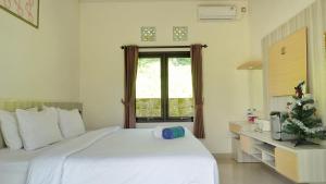 a bedroom with a white bed and a window at Kubu Kiku Megati in Selemadeg