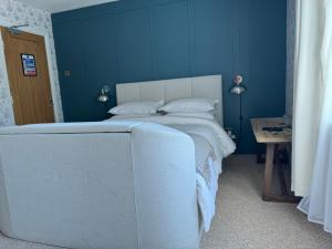 a blue bedroom with a white bed and a table at Whichcote Arms Hotel in Sleaford