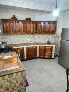 a kitchen with wooden cabinets and a refrigerator at Skikda in Cité el ʼArbi Ben Mhîdi