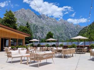 a restaurant with tables and chairs with mountains in the background at AMZA Valbona Mountain Retreat in Valbonë