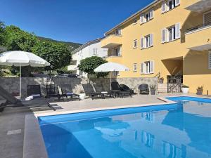 a swimming pool with chairs and umbrellas next to a building at Apartments Gorica 2 in Baška