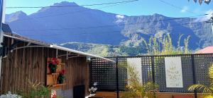 a house with a fence with a mountain in the background at Le Papyrus in Cilaos