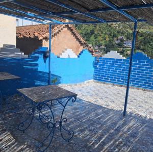 a patio with a table and a blue wall at Bleu Chefchaouen in Chefchaouen +3 photos