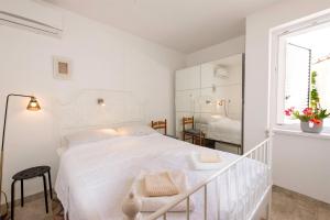 a white bedroom with a white bed and a window at Apartment Pasarela in Gajac