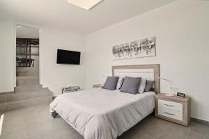 a white bedroom with a bed and a staircase at Apartamento Guada in Tao +13 photos