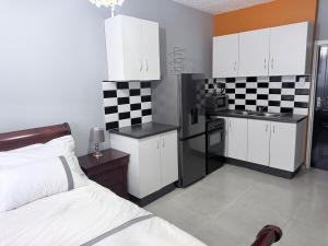 a bedroom with a bed and a kitchen with white cabinets at CCV Beach House in Bay View