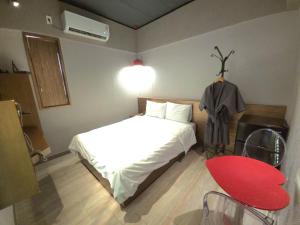 a bedroom with a white bed and a red chair at AREA HoTEL in Yeongju