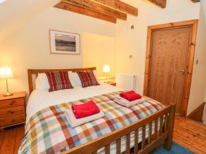 a bedroom with a bed with two red pillows on it at Elm Cottage in Aberfeldy