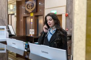 a woman talking on a cell phone in front of two computers at Carlton Tower Hotel Kuwait in Kuwait