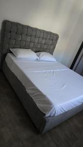 a large bed with a gray headboard and white sheets at Le beau Mazagran in Mostaganem