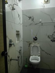 a bathroom with a white toilet in a room at Seabay Bliss Varkala by Ojes in Varkala