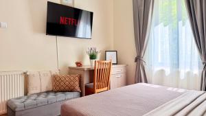 a bedroom with a bed and a chair and a tv at Stavilar Hotel - Charming Stay Just Steps Away from Peles Castle in Sinaia in Sinaia