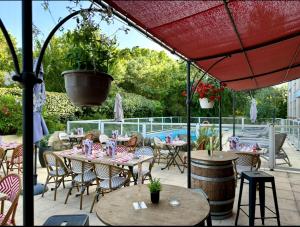 a patio with tables and chairs and a pool at Kyriad Aix Les Milles - Plan de Campagne in Bouc-Bel-Air