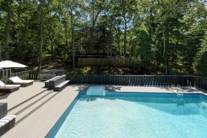 a swimming pool in a yard with a wooden deck at Villa Sapphire Bay in Sag Harbor