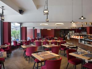 a restaurant with wooden tables and red chairs at IBIS STYLES KINSHASA in Kinshasa