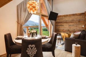 a dining room with a table and chairs and a large window at Apartament Stary Drewniany Białka Ski Resort -obok Termy Bania i Kotelnica in Białka Tatrzańska
