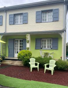 two white chairs sitting in front of a house at Le camphrier in Salazie