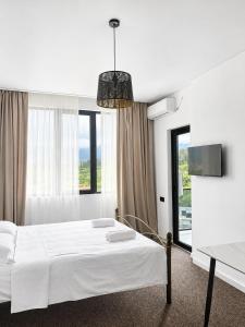 a white bedroom with a bed and a large window at Complex DEL MAR in Chakvi