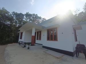 a small white house with trees in the background at Ithal Villa - Home Stay in Wayanad