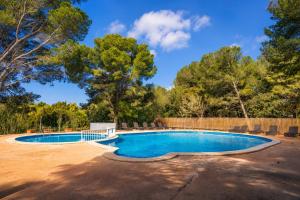 a swimming pool in a yard with trees in the background at Kampaoh Menorca in Cala Galdana