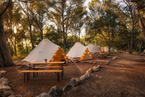 a row of tents sitting in a forest at Kampaoh Menorca in Cala Galdana