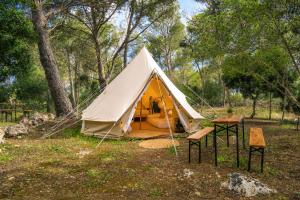 a tent in a field with two chairs and a table at Kampaoh Menorca in Cala Galdana