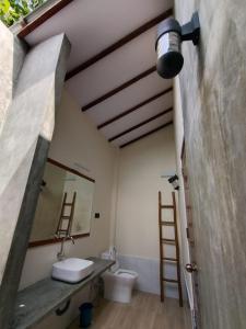 a bathroom with a sink and a mirror and a toilet at Madi Beach Guesthouse in Maalhos
