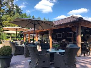 a patio with tables and chairs and an umbrella at Ons Boshuys C18 in Garderen