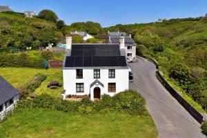 a white house with a black roof on a road at Finest Retreats - Gladstone in Aberdaron