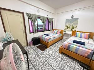 a bedroom with two beds and a fan at Madam Guesthouse in Krabi