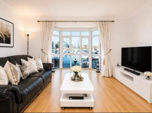 a living room with a black leather couch and a tv at Waterside House in Southampton