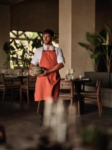a man in an apron holding a plate in a restaurant at OKU Andalusia in La Alcaidesa +217 photos