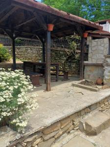 an outdoor patio with a stone wall and a woodenilion at Кацарила in Gabrovo