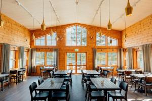 a restaurant with wooden tables and chairs and windows at Pinetree Lodge in Kangos