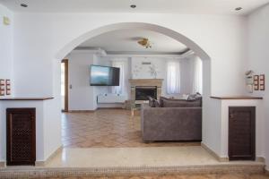 a living room with a couch and a flat screen tv at Villa Kallithea Sunrise in Koskinou