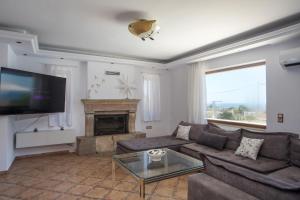 a living room with a couch and a fireplace at Villa Kallithea Sunrise in Koskinou