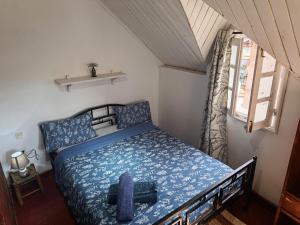 a bedroom with a bed with blue sheets and a window at La lanterne in Antananarivo