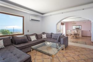 a living room with a couch and a glass table at Villa Kallithea Sunrise in Koskinou