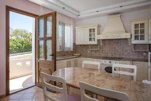 a kitchen with a table and chairs and a window at Villa Kallithea Sunrise in Koskinou +47 photos