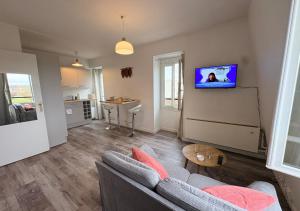 a living room with a couch and a tv on a wall at Studio central équipé in Compiègne