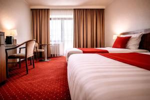 a hotel room with two beds and a desk at REDBERRY Hotel - Düsseldorf - Neuss in Neuss +8 photos