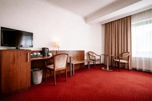 a hotel room with a table and chairs and a television at REDBERRY Hotel - Düsseldorf - Neuss in Neuss