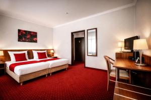a hotel room with a bed and a desk and a television at REDBERRY Hotel - Düsseldorf - Neuss in Neuss