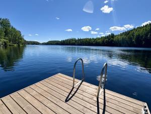 a dock with two metal chairs on a lake at Iken Mökit in Heinola
