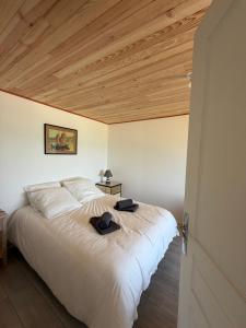 a bedroom with a large white bed with a wooden ceiling at La Bournonville in Ault