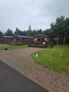a group of cottages in a field with grass at Chillingham lodge with hot tub Felmoor Park in Felton