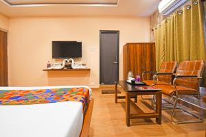 a room with a bed and a table and a tv at FabHotel Royal Lagoon in Bhubaneshwar
